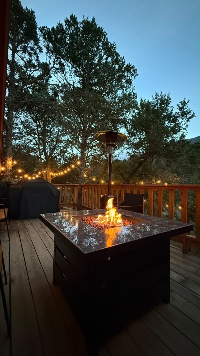 Fogatero encendido de noche en la terraza de la Cabaña Alpina M3, con luces entre los pinos